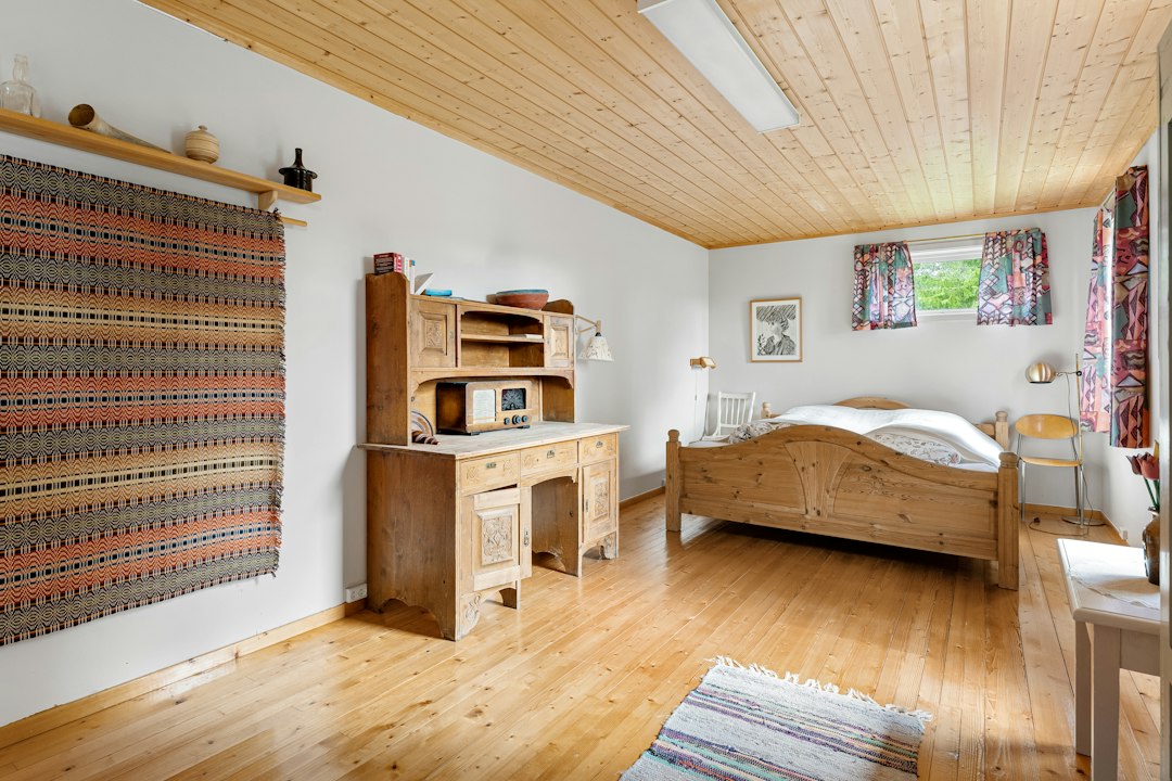 A bedroom with a bed, desk, and dresser